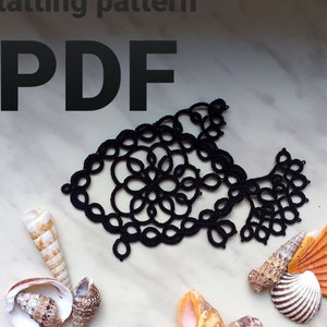 Peut inclure: Motif de dentelle noire en forme de poisson avec un motif floral. Le motif est sur une surface en marbre blanc avec des coquillages.