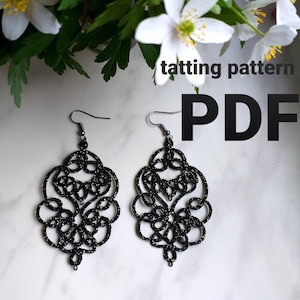May include: A pair of black tatting earrings with a delicate, intricate design. The earrings are shown against a white background with white flowers.