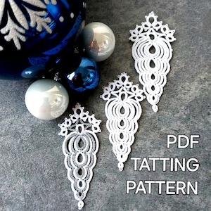 Puede incluir: Primer plano de adornos de encaje blanco hechos a mano con intrincados diseños, junto a bolas de Navidad azules y plateadas. Los adornos tienen forma de lágrima. El texto dice "PDF TATTING PATTERN".