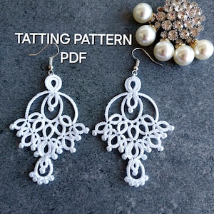 May include: White, handmade tatting earrings with a chandelier design. The earrings feature intricate lace patterns and small bead accents. The image also includes a decorative brooch with pearls and rhinestones, and the text "TATTTING PATTERN PDF".