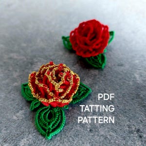 Puede incluir: Dos motivos de rosas hechos a mano con técnica de frivolité, con pétalos de hilo rojo vibrante, bordes dorados metálicos y pequeñas cuentas rojas. Cada rosa tiene hojas verdes. El texto PDF TATTING PATTERN aparece en blanco a la derecha.