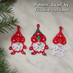 May include: Three red, white and green crocheted ornaments shaped like dwarves. The ornaments have white beads for beards and a pearl bead for a nose. The ornaments are on a white surface. The text "Pattern "Dwarf" by Frivolite con sabor" is above the ornaments.