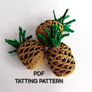 May include: Three handmade, crocheted pineapples. The pineapples are gold with black accents and green leafy tops. The text "PDF TATTTING PATTERN" is at the bottom of the image.