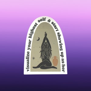 May include: A sticker with a white border and a beige background featuring a silhouette of a woman with her arms raised, a crescent moon, and stars. The text around the border reads "visualize your highest self & start showing up as her."