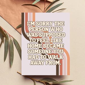 May include: A rectangular greeting card featuring a light purple background with vertical, wavy stripes in shades of brown, peach, and cream. The text reads: I'M SORRY THE PERSON WHO WAS SUPPOSED TO FEEL LIKE HOME BECAME SOMEONE YOU HAD TO WALK AWAY FROM.