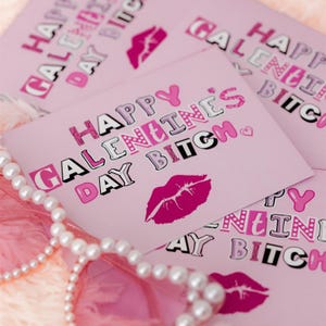 May include: Pink card with the text "Happy Galentine's Day Bitch" in black and pink letters with a pink lip print.