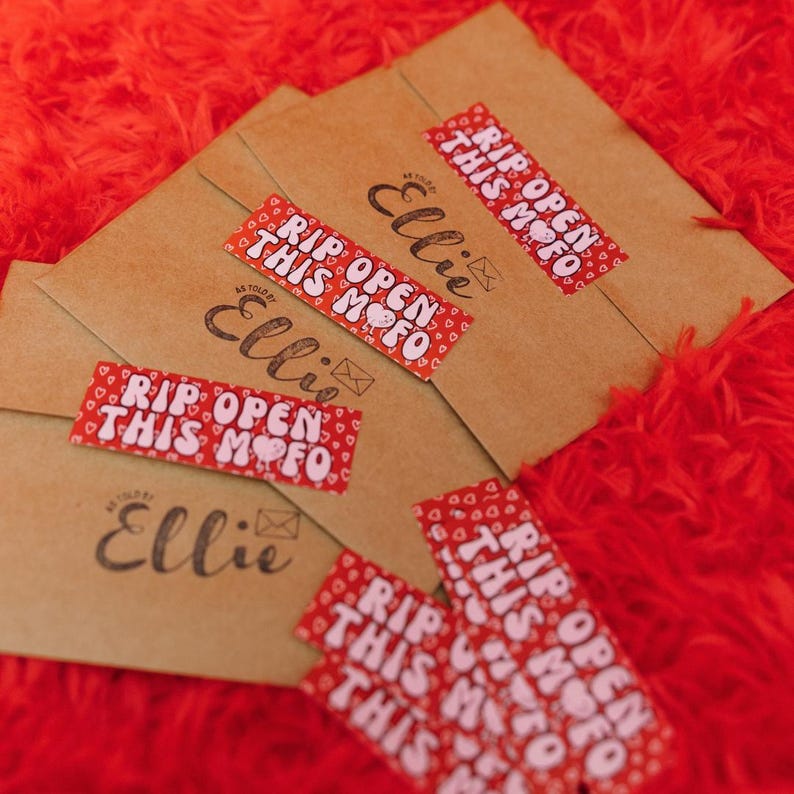 May include: Multiple brown envelopes with red and white stickers that say "Rip Open This Mofo" and the name "Ellie" written on each envelope.