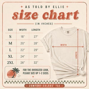 Op de afbeelding: Een maattabel voor een t-shirt met de tekst AS TOLD BY ELLIE, size chart en IN INCHES. Een tabel toont de maten S tot 2XL met breedte- en lengtematen in inches. Een beige t-shirt wordt getoond met pijlen voor de breedte en lengte.