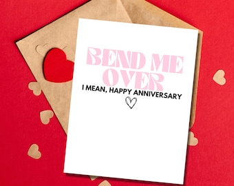 May include: A white card with the text "Bend Me Over I Mean, Happy Anniversary" in pink and black lettering. The card is on a brown envelope with a red heart on it.