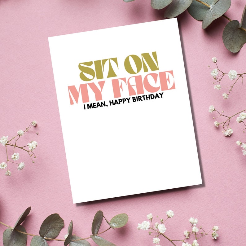 May include: A white card with the text "Sit on my face, I mean, Happy Birthday" in pink and gold letters.
