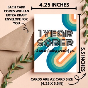 Op de afbeelding: Een witte kaart met een kleurrijk regenboogontwerp en de tekst "1 YEAR SOBER I am so fucking proud of you". De kaart is 4,25 inch bij 5,5 inch.