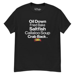 Może przedstawiać: Czarny T-shirt z białym tekstem, który brzmi "Oil Down, Fried Bake, Saltfish, Callaloo Soup, Crab Back." Tekst jest wyśrodkowany na koszulce. Mała jamajska flaga znajduje się pod tekstem.