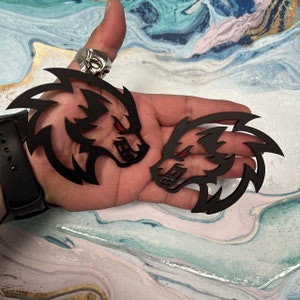 May include: Two black wolf head decals with red eyes. The decals are cut out and have a detailed design.