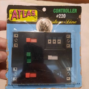 May include: A vintage Atlas Custom-Line Controller #220, packaged on a blue card. The black controller features red, green, and white switches, along with connection terminals. The package includes the Atlas logo and text that reads "Made in U.S.A."