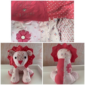 May include: Pink and white baby clothes set with a pink lion stuffed animal. The clothes have a floral print and the text "Little Miss Sunshine".