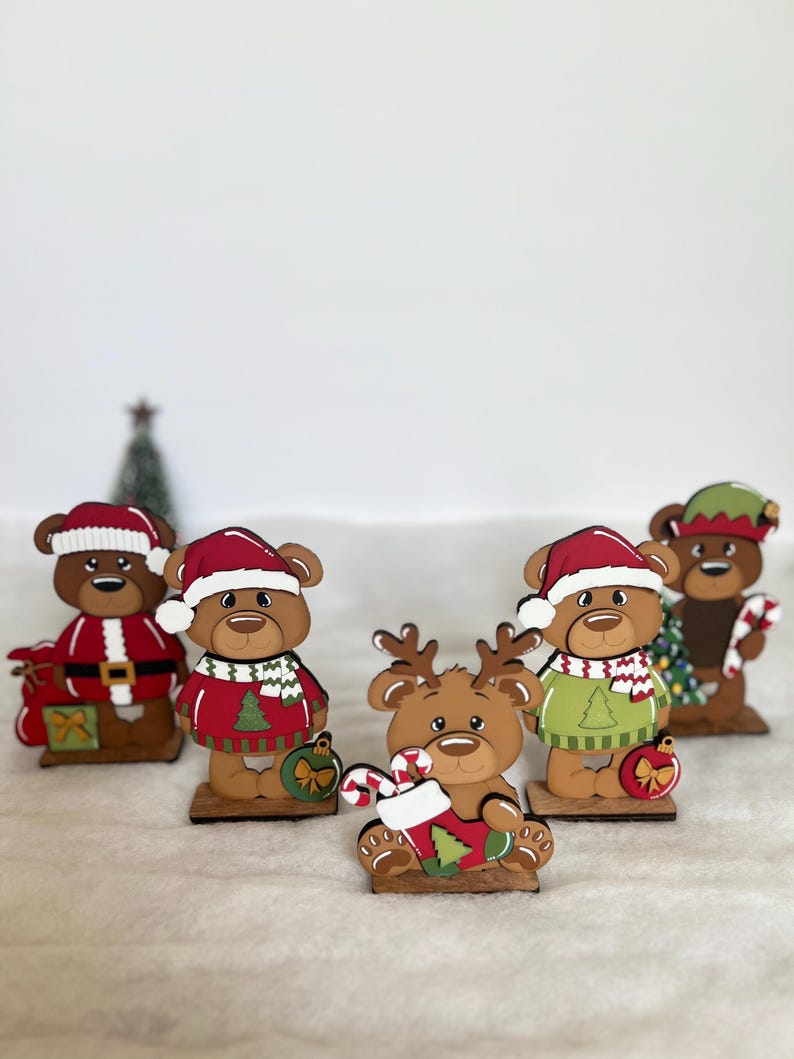 Puede incluir: Un conjunto de figuras de osos navide&ntilde;os de madera. Cada oso viste atuendos festivos, incluyendo gorros de Pap&aacute; Noel y su&eacute;teres. Algunos osos sostienen bastones de caramelo o adornos, creando una alegre exhibici&oacute;n navide&ntilde;a.