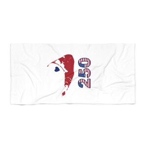 May include: A white rectangular towel featuring a graphic of a red, white, and blue gnome hat with a small blue heart, positioned next to the number 250, which is filled with a red, white, and blue American flag pattern and stars.