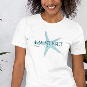 Peut inclure: Un t-shirt blanc avec une étoile de mer bleue et le texte "LAW STREET" imprimé sur le devant.