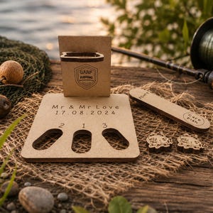 May include: A light brown wooden display stand featuring the engraved text "Mr & Mr Love 17.08.2024" and "Carp Fishing" with three oval cutouts labelled 2, 1, and 3. Included are a small rectangular wooden piece and two small fish-shaped wooden tokens.