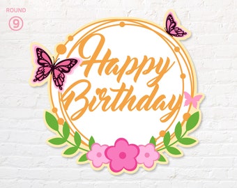 Puede incluir: Un adorno para pastel redondo de papel blanco con un círculo dorado y las palabras "Happy Birthday" en escritura dorada. El círculo está decorado con mariposas y flores rosas.