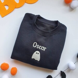 Black crew neck sweatshirt, embroidered with glow in the dark ghost personalised with childs name. Machine embroidered in the UK