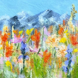 May include: An oil painting featuring a vibrant meadow of wildflowers in shades of orange, yellow, purple, and green, set against a backdrop of textured, dark blue mountains under a clear, light blue sky with visible, thick brushstrokes.