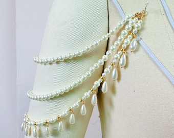 May include: A white pearl armlet with gold accents and dangling pearl drops. The armlet is made of multiple strands of pearls and is worn on the upper arm.