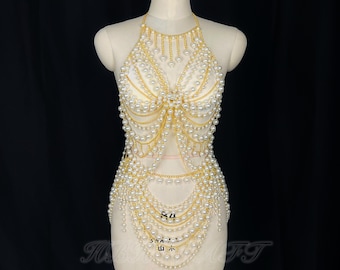 May include: A gold chain body jewelry piece with white pearls. The chain is layered and has a halter neck style.