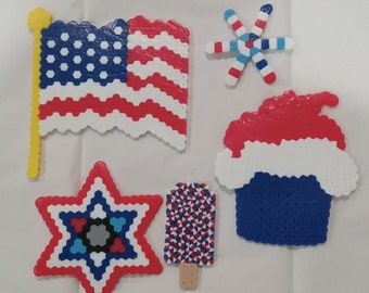 May include: A set of six red, white, and blue bead crafts. The crafts include a star, a flag, a snowflake, a cupcake, and a popsicle.