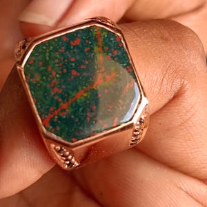 Op de afbeelding: Een vierkante ring met een groene, rode en oranje edelsteen gezet in een roségouden band.