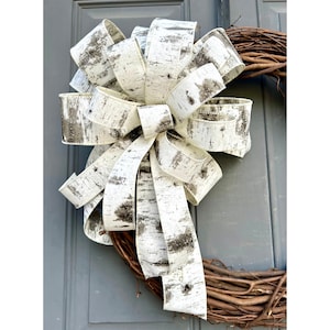 May include: A white and brown birch bark patterned ribbon bow tied on a brown grapevine wreath.