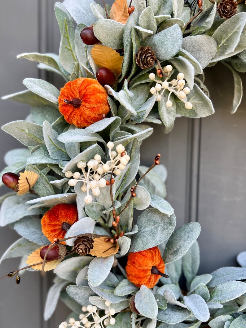 Puede incluir: Una corona de oto&ntilde;o con vegetaci&oacute;n artificial, peque&ntilde;as calabazas, bellotas y pi&ntilde;as.