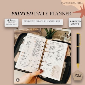 Op de afbeelding: Een gedrukte dagelijkse planner navulling met 45 pagina's, ontworpen voor de grootte van een persoonlijke ringplanner. De open planner toont dagelijkse schema pagina's met handgeschreven notities. Een zwarte en gouden pen wordt naast de planner weergegeven.