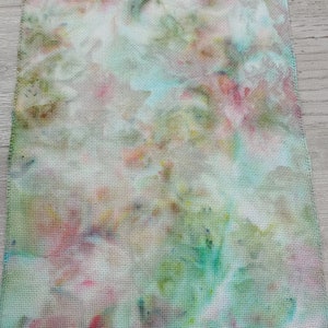 May include: A piece of white fabric with a tie-dye pattern in shades of pink, blue, green, and yellow.