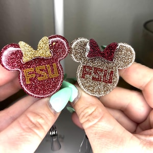 May include: Two glitter mouse ear keychains with FSU written on them. One is red with gold glitter and the other is gold with red glitter.