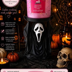 以下が含まれることがあります： Bath & Body WorksのMilk Bar Birthday Cakeというラベルが貼られたピンク色の3芯キャンドル。白いゴーストマスクを被ったフード付きの人物の形をした黒いキャンドルホルダーの上に置かれています。キャンドルにはカラフルなスプリンクルが散りばめられ、3つの芯に火が灯っています。