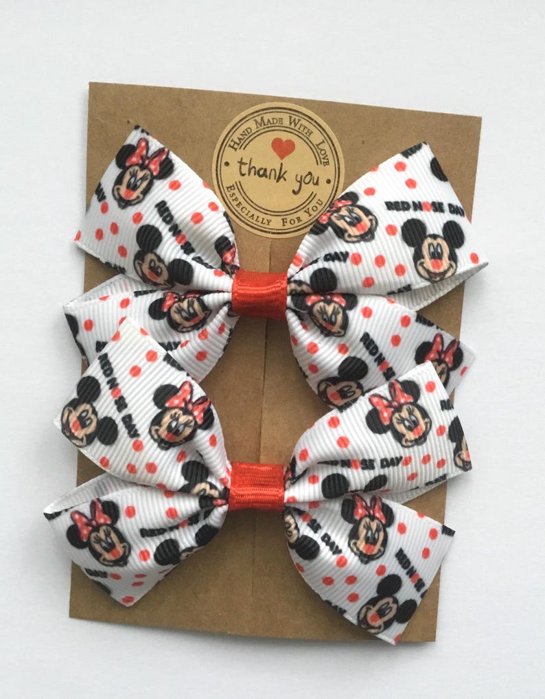 Minnie Mouse themed Red Nose Day hair bows, white ribbon with red polka dots and character print. Cute Disney-inspired charity event accessories.