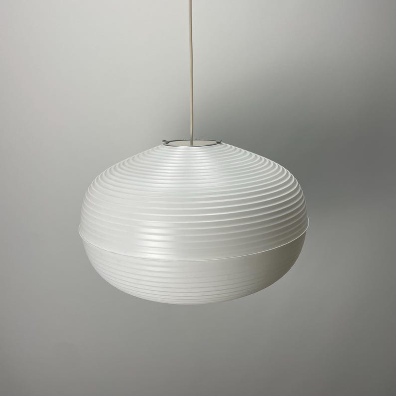 Puede incluir: Una l&aacute;mpara colgante esf&eacute;rica blanca con un dise&ntilde;o acanalado. La luz cuelga de un cable fino de color blanco roto y una fijaci&oacute;n met&aacute;lica circular. La l&aacute;mpara es de dise&ntilde;o moderno, adecuada para la iluminaci&oacute;n interior.