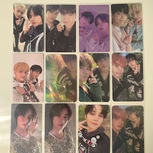May include: A collection of K-pop photo cards featuring various members of a boy band. The cards showcase individual portraits and group shots, with the subjects posing in diverse outfits and settings. The images have a glossy finish.