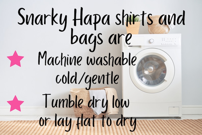 May include: A white washing machine with a white door and a silver knob. The washing machine is in a laundry room with a white wall and a brown rug. The text on the wall reads "Snarky Hapa shirts and bags are Machine washable cold/gentle Tumble dry low or lay flat to dry".
