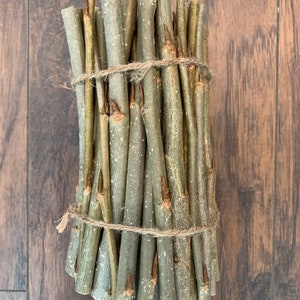 May include: A bundle of thin, light brown twigs tied together with twine. The twigs are about 10 inches long and have a rough, natural texture.