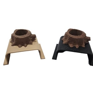 May include: Two wooden tree stump shaped holders, one on a beige base and one on a black base. Both holders have a small hollow in the top.