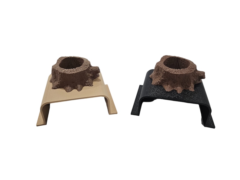 May include: Two wooden tree stump shaped holders, one on a beige base and one on a black base. Both holders have a small hollow in the top.