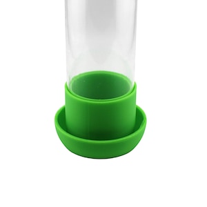 Peut inclure: Un distributeur d'aliments en verre transparent avec une base en silicone verte et un anneau en silicone vert autour du haut du verre.