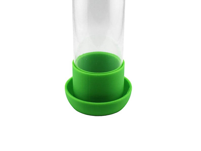 Peut inclure: Un distributeur d'aliments en verre transparent avec une base en silicone verte et un anneau en silicone vert autour du haut du verre.