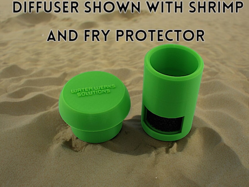 Peut inclure: Deux diffuseurs d'aquarium en plastique vert, l'un avec un dessus rond et l'autre de forme cylindrique. Le diffuseur rond porte l'inscription "Water Werks Solutions". Le diffuseur cylindrique contient une &eacute;ponge noire. Les deux diffuseurs sont pos&eacute;s sur une surface sablonneuse.