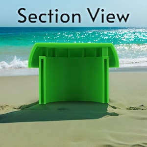 Peut inclure: Vue en coupe d'un objet rond en plastique vert avec un dessus plat et un centre creux. L'objet est pos&eacute; sur une plage de sable.