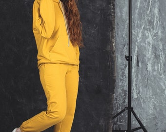 Solid yellow tracksuit set for women. Classic loose oversized hoodie and jogging pants. Matching cotton sweatpants and sweatshirt.