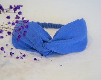 May include: A blue fabric headband with a knotted design. The headband is made of a soft, stretchy material and is perfect for keeping hair out of your face.
