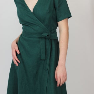 May include: A dark green wrap dress with short sleeves and a tie belt.